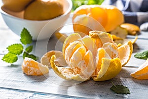 Tangerines with peel and mellisa herbs on table. Ripe fresh tropical fruit on wooden board