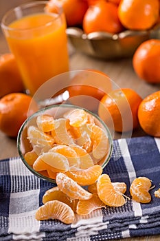 Tangerines, peeled tangerine and tangerine slices on a blue cloth. Mandarine juice