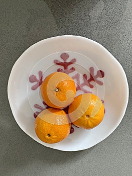 Tangerines in a white bowl with holiday snowflake design