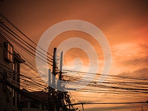 Tangle cable and electricity post on sunset background.