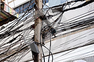 Tangle of Electrical cables and Communication wires on electric pole with building in the city