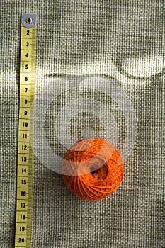 Tangle of orange thread and a measuring tape on a green cloth