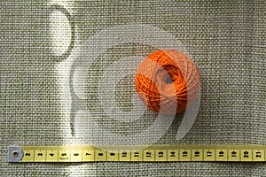 Tangle of orange thread and a measuring tape on a green cloth