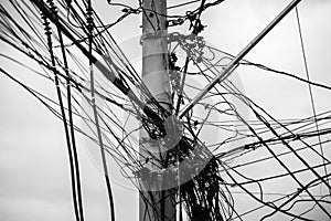 Tangle of wires and cables on a pole against the clear sky