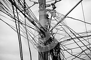 Tangle of wires and cables on a pole against the clear sky photo