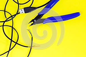 Tangled charger wires. Black wire on a yellow background with nippers