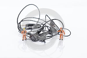 Tangled earphones cable with miniature worker isolate on white background