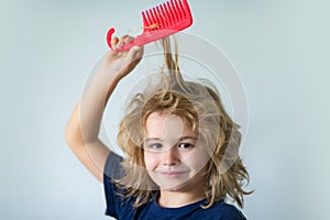 Tangled kids hair. Cute child with comb. Blonde kid combs unruly hair. Kid boy with tangled long hair.