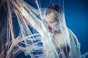 Tangled, naked man trapped in a huge spider web