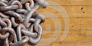 Tangled old rusty metal chain on wooden background - concept with copy space