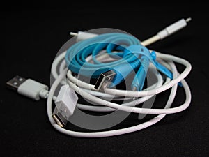 Tangled roll of USB wires over black background