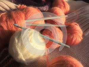 Tangles, snarls. Balls of yarn and thread, knitted clothes, knitting needles and crochet hooks. Pink, purple, red and white
