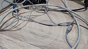 Tangling earphone and charging cable on wooden background