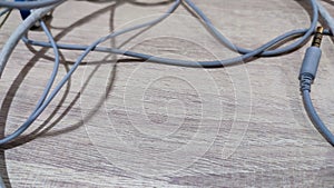 Tangling earphone and charging cable on wooden background