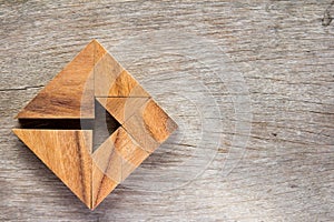 Tangram puzzle as arrow in square shape on wood background Co photo