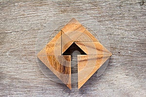 Tangram puzzle as arrow in square shape on wood background photo