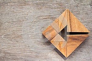 Tangram puzzle as arrow in square shape on wood background photo