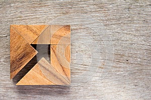 Tangram puzzle as arrow in square shape on wooden background photo