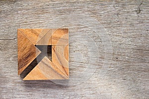Tangram puzzle as arrow in square shape on wooden background Co photo