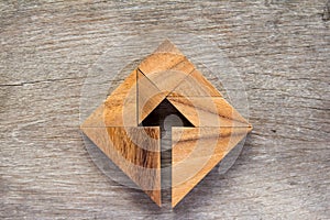 Tangram puzzle as arrow in square shape on wood background Co photo
