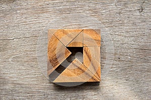 Tangram puzzle as arrow in square shape on wood background photo