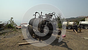 Tank crusted over with oil and gunk sits along cliffside construction site