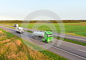 Tank transport of liquid, foodstuff. Metal chrome cistern tanker for food transportation on highway on sunset background. Soft
