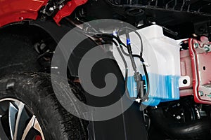 Tank with washer fluid and a motor in the car body