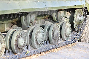 Tank wheels close-up. Iron tracks of a heavy military tank. Iron caterpillars and wheels of a military heavy tank. View of the