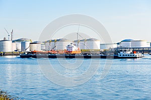 Tanker barge sailing past an oil dock in the port of Rotterdam