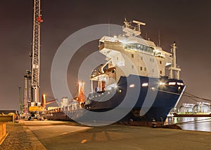 Tanker with a large crane at illuminated embankment at night, Port of Antwerp
