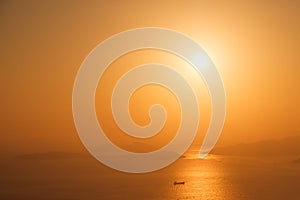 Tanker ship on ocean horizon with sunset sky and coast background