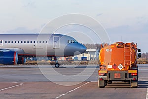 Tanker truck with aviation fuel passes a taxiing plane leaving for a flight