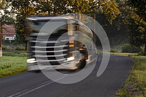 Tanker truck driving fast on the asphalt road in the morning