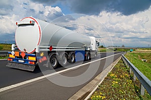 A tanker truck on the highway leading through the countryside