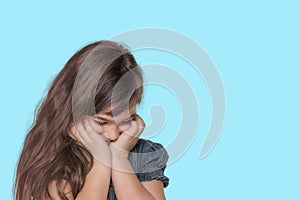 Tanned ashamed little girl is posing on cyan background