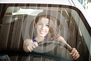 Tanned brunette looking through car windscreen smiling