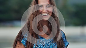 Tanned face of a charming young girl with long hair, which sensually poses on the camera in the evening on the coast