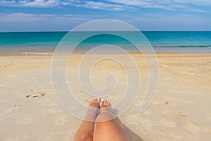 Tanned female legs on the beach by the sea. Woman legs sunbathing on the beach