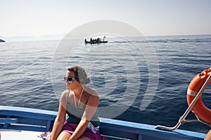 A tanned girl with sunglasses sitting on a motorboat offshore. Boat ride.