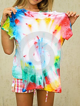 Tanned girl trying on a t-shirt in the style of tie-dye.