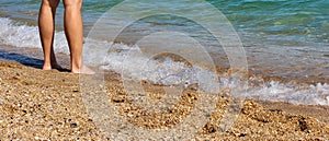 Tanned legs in the sea waves on the beach. The concept of recreation. Place for your text