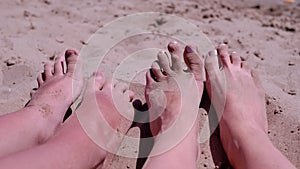 Tanned Red Bare Feet of Mother and Child in Sand Lies on a Sandy Beach