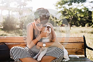 Tanned smiling lady in elegant wristwatch embracing beagle dog during rest in park in morning, Charming woman in