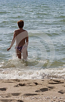 Tanned topless woman going to swim in the sea