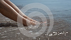 Tanned woman legs smeared beach sand on sunlight closeup. Sexy lady sunbathing.