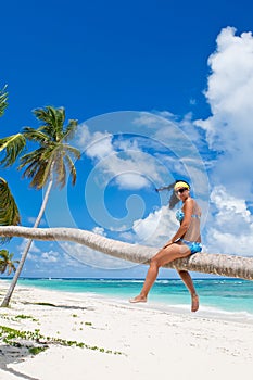 Tanned woman sitting on a palm white sand beach