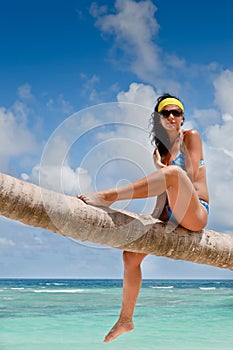 Tanned woman sitting on a palm white sand beach