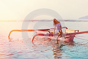 Tanned woman tilted her head while in the boat at sunset. in soft focus
