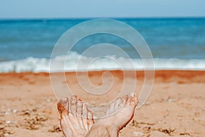 women's feet on the beach by the sea